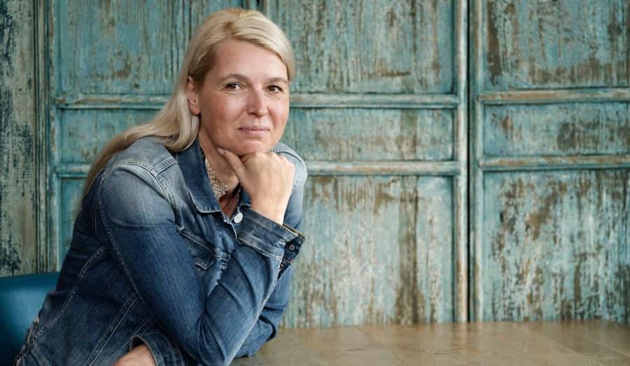 Portretfoto van Ilse zittend aan een tafel. Ze gebruikt SpeediCath Compact Vrouw voor haar blaasproblemen.