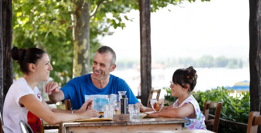 Andrea zit samen met zijn familie aan een tafel in een restaurant. Als je vragen of zorgen hebt over je blaas en darmen wanneer je MS hebt, neem dan contact op met Coloplast Care voor ondersteuning. 