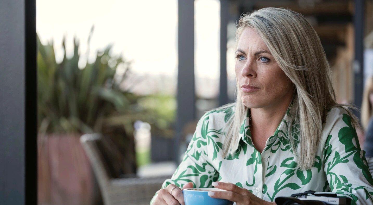 Portretfoto van Laura die aan een tafel zit met een kopje koffie. Dit artikel biedt ondersteuning en praktische suggesties om je te helpen bij je routines rondom katheteriseren en darmspoelen. 